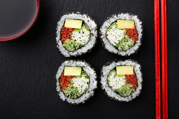 Sushi Rolls with vegetables on a dark background. Sushi set on a stone plate and dark concrete background. Sushi roll set and chopsticks. Fresh Japanese cuisine. asian food. Sushi image for menu. close up