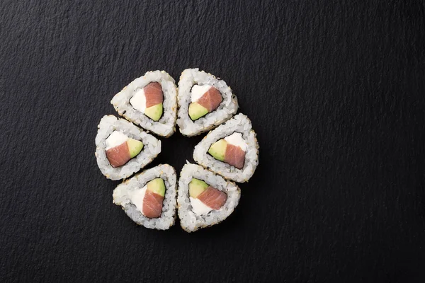 Sushi Rolls with tuna on a dark background. Japanese traditional roll with tuna. Sushi set on a stone plate and dark concrete background. Sushi roll set and chopsticks. Fresh Japanese cuisine. asian food. Sushi image for menu. close up