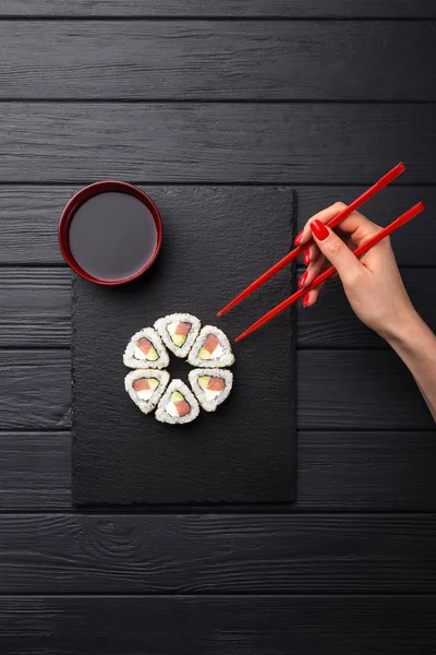 女人拿着筷子做寿司 一个拿着筷子的年轻女人 被黑色隔离了 Sushi Roll Woman Hand Holding Chopsticks — 图库照片