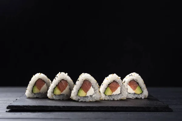Sushi Rolls with tuna on a dark background. Japanese traditional roll with tuna. Sushi set on a stone plate and dark concrete background. Sushi roll set and chopsticks. Fresh Japanese cuisine. asian food. Sushi image for menu. close up