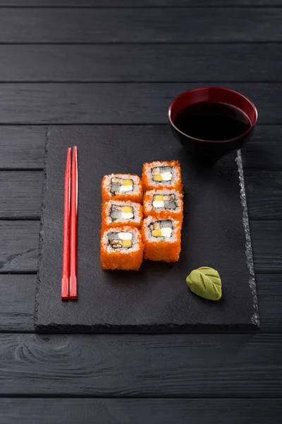 Sushi set. maki, gunkan and sushi rolls served on stone slate. Sushi set on a stone plate and dark concrete background. Sushi roll set and chopsticks. Fresh Japanese cuisine. asian food. Sushi image for menu. close up