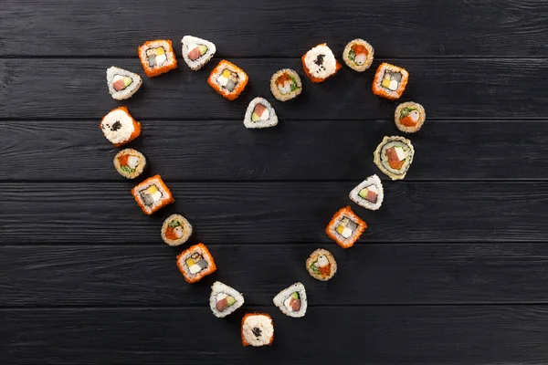 Sushi set in the shape of a heart. Valentine's Day. maki, gunkan and sushi rolls served on stone slate. Sushi set on a stone plate and dark concrete background. Sushi roll set and chopsticks. Fresh Japanese cuisine. asian food. Sushi image for menu