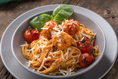 Geleneksel İtalyan makarnası eski ahşap bir masada servis edilir. Köfteli makarna, parmesan peyniri ve otlar. Ev yapımı lezzetli İtalyan geleneksel makarnası kırsal bir masada akşam yemeği için. İtalyan mutfağı...