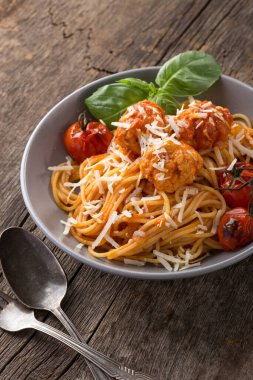 Geleneksel İtalyan makarnası eski ahşap bir masada servis edilir. Köfteli makarna, parmesan peyniri ve otlar. Ev yapımı lezzetli İtalyan geleneksel makarnası kırsal bir masada akşam yemeği için. İtalyan mutfağı..
