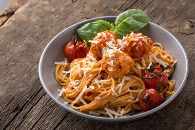 Geleneksel İtalyan makarnası eski ahşap bir masada servis edilir. Köfteli makarna, parmesan peyniri ve otlar. Ev yapımı lezzetli İtalyan geleneksel makarnası kırsal bir masada akşam yemeği için. İtalyan mutfağı..