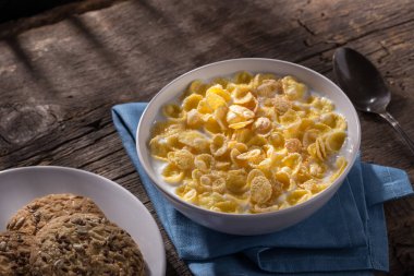 Mısır gevreğiyle kahvaltı. Sütlü gevrek. Eski ahşap bir masada bir tabak mısır gevreği ve süt. Kahvaltı için mükemmel. Metin için boş alan.