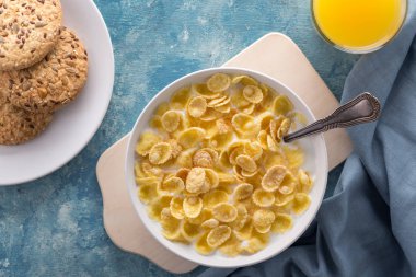 Mısır gevreğiyle kahvaltı. Sütlü gevrek. Mavi bir masada bir tabak mısır gevreği ve süt. Kahvaltı için mükemmel. Metin için boş alan. Yukarıdan bak. Üst Manzara. Yakın çekim..
