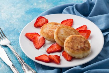 Peynirli ve çilekli krep. Çilekli ve kremalı peynirli kek. Krepler mavi bir masada servis edilir. Kahvaltı için harika. Yakın plan çekim. Metin için boş alan.