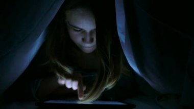 Blaket altında dijital tablet yazarak kız. 