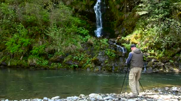 Kameraman nedaleko malého vodopádu. — Stock video