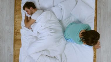 Mutsuz bir çift. Depresif mutsuz kadın yatakta, onun boyfriend(husband) uyurken oturuyordu. Yukarıdan görüntülemek.