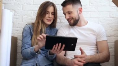 Mutlu çift planya yeni interiour. Dijital tablet kullanma. Kaymak vurdu.