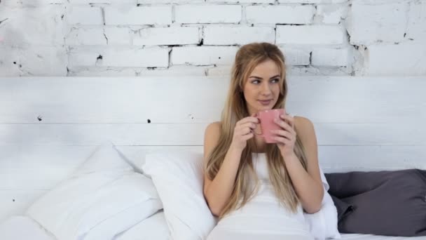 年轻妇女喝咖啡从粉红色杯子 微笑和看照相机 — 图库视频影像