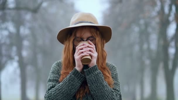 Młoda Ruda Kobieta Kapeluszu Pijąca Kawę Spacerująca Jesiennym Parku Strzał — Wideo stockowe