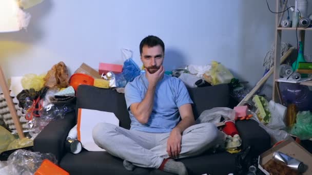 Sério Nenhum Homem Emotivo Sentado Sofá Sala Cheia Lixo Olhar — Vídeo de Stock