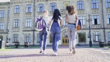 Kız arkadaşlar (veya öğrenciler) koleje yakın yürüyorlar. Konuşuyor, gülüyor ve gülümsüyor. El kamerasıyla. Arkadan bak..