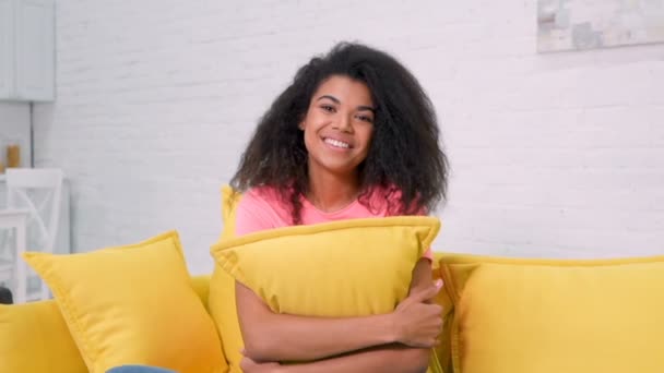 Sonriente Joven Afroamericana Sentada Sofá Abrazando Almohada Sonriendo Emoción Acogedora — Vídeos de Stock