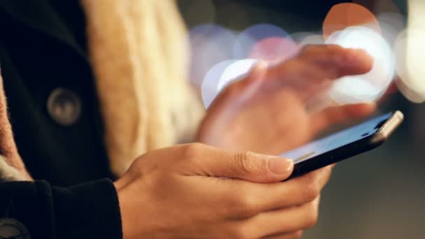 Gros plan de mains féminines tenant un smartphone dans la rue du soir .