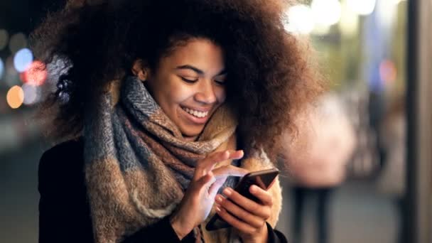 Junge Afroamerikanerin Hält Smartphone Der Hand Schaut Und Schreibt Sms — Stockvideo
