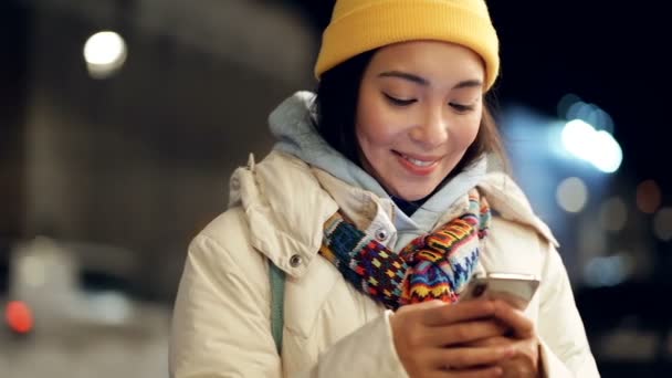 Smiley Asiatisk Kvinna Kvällen Vintern Gatan Hålla Mobiltelefon Titta Den — Stockvideo