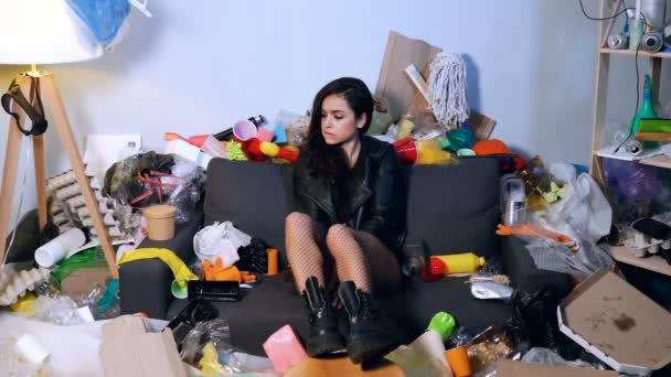 ゴミを抱えてゴミ箱に座って汚染された部屋に座っている女性 リサイクル 清掃の概念 — ストック動画