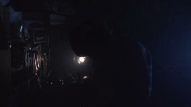 Kaynakçı adam işyerine gidiyor ve metalle çalışıyor. Elektrot kaynaklamasından kıvılcımlar ve parıltılar. Yavaş çekim.