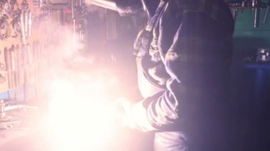 Güvenlik maskesi ve eldivenli kaynakçı iş yerinde metalle çalışıyor. Yavaş çekim.
