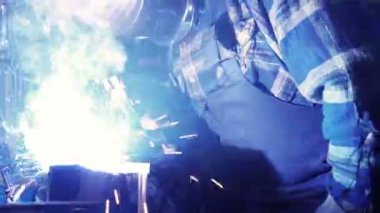 Metalle çalışan kaynakçı. Elektrot kaynaklamasından kıvılcımlar ve parıltılar. El kamerasıyla..