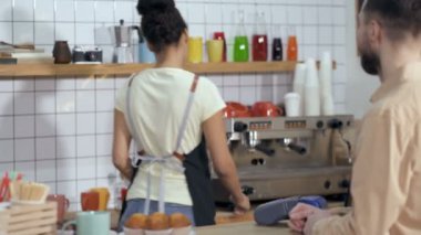 Kahveci kadın kahve dükkanında müşteriye servis yapıyor, ona kahve hazırlıyor ve ücretsiz ödeme alıyor.. 