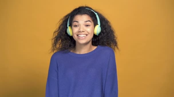 幸せなアフロ系アメリカ人女性の肖像画 カメラを見て ヘッドフォンで音楽を聴く スローモーション — ストック動画