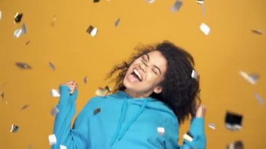 Mutlu Afro-Amerikan kadın seviniyor, eğleniyor ve dans ediyor, kahve düşüyor. Yavaş çekimde. Sarı arkaplan.