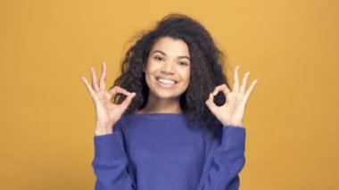Afro-Amerikan kadın portresi tamam işareti gösteriyor. Sarı arkaplan.