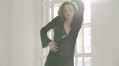 İç çamaşırı giymiş genç bir kadın poz veriyor. Yavaş çekim.