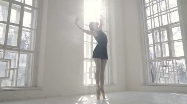 Pencere kenarında duran ve dans provası yapan bir balerin. Yavaş çekim.