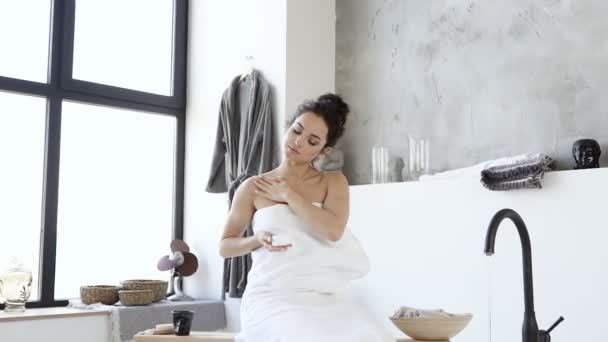 护肤迷人的年轻女人坐在浴缸上 肩膀上涂着奶油 慢动作 — 图库视频影像