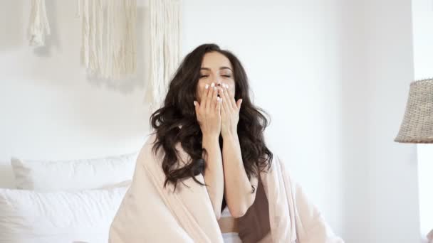 魅力的なブルネットの女性は 毛布の下に座って 空気のキスをしています 手持ち撮影 — ストック動画