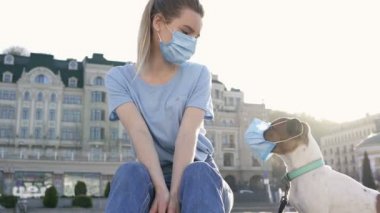 Sarışın kadın ve dışarıda maskeli Jack Russell köpeği..