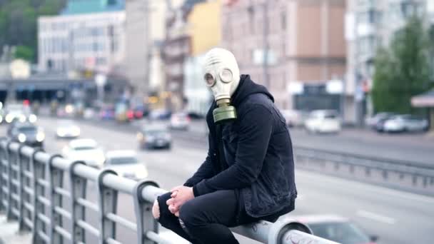 戴防毒面具的男人坐在车路旁边的栏杆上 — 图库视频影像