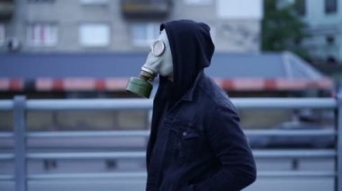 Gaz maskeli bir adam akşam caddesinde hızla yürüyor. Yavaş çekim.