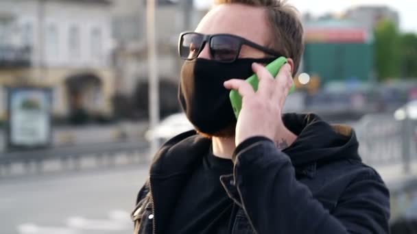 Hombre Con Mascarilla Negra Caminando Por Calle Hablando Por Teléfono — Vídeos de Stock