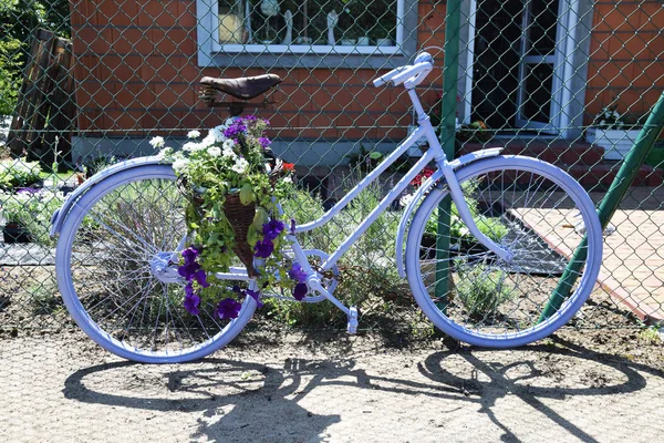 Велосипед с корзиной цветов, стоящих у забора — стоковое фото