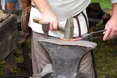 Açık havada bir çekiç ile çalışırken demirci