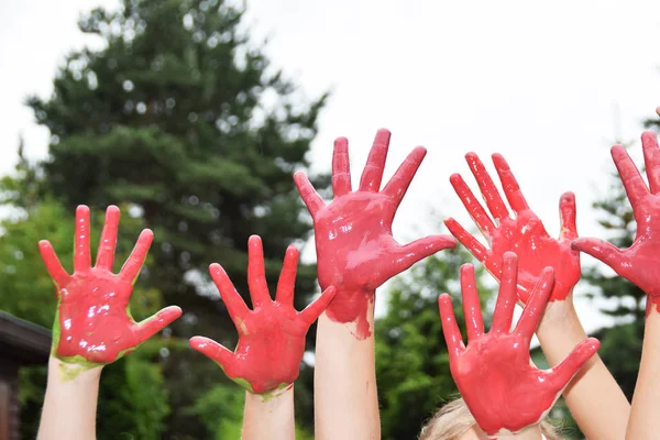 red hands of children playing staining