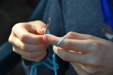 Tığ üzerine mavi yün zinciri yapan kirli eller