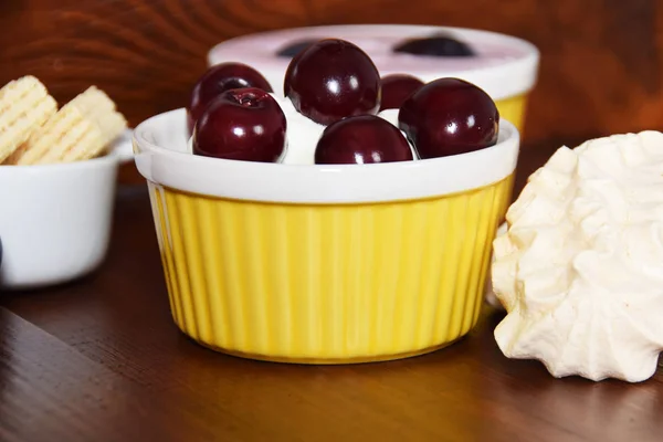 Cakes and bowls with cherries on sweet cream