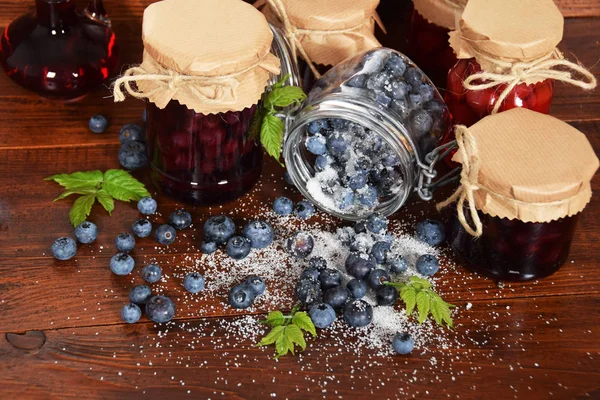 Spilled sugar berries on a wooden table and a jug of berry juice — Stock Photo, Image