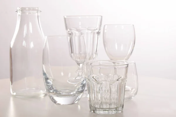 Vasos y vasos de cristal vacíos y una botella — Foto de Stock