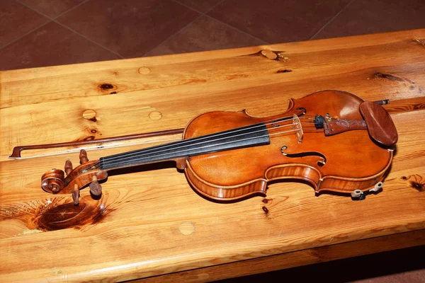 Velho violino em um velho banco de madeira em uma igreja — Fotografia de Stock