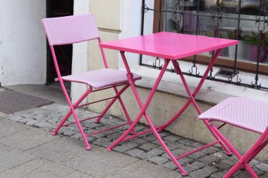 Pembe metal sandalye ve masa önünde kaldırımda ayarla