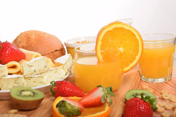 Un vaso de jugo de naranja entre el queso amarillo y el cere del desayuno — Foto de Stock